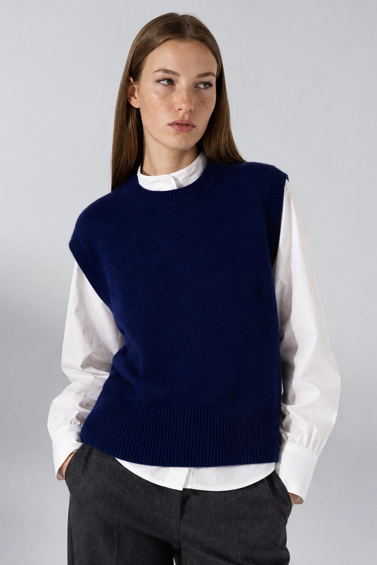Pull sans manches Inès bleu marine en laine mérinos porté avec un pantalon gris, Huguet paris